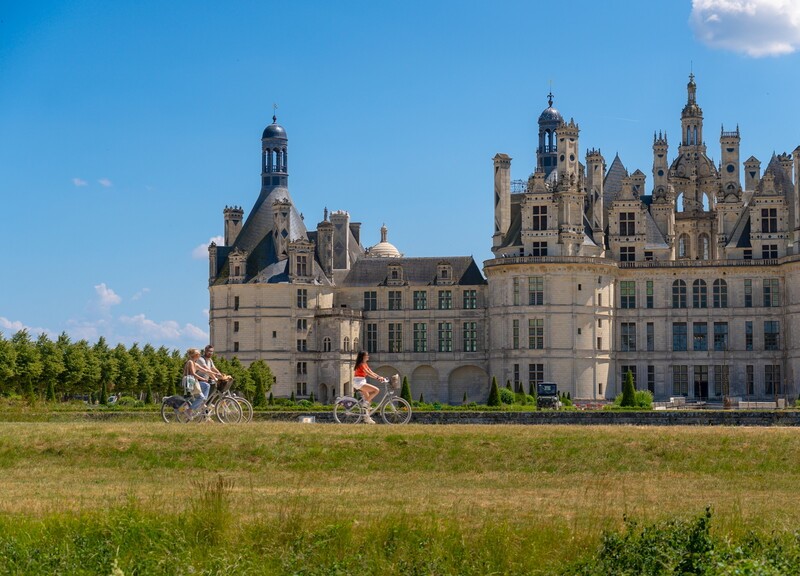 A vélo devant le château de Chambord - Crédit photo : Les Coflocs